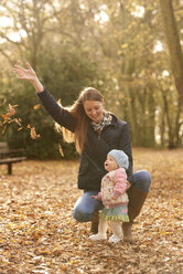 Mid erwachsene Frau und Baby Tochter beobachten Herbst Blätter im Park - CUF31539