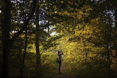 Volle Seitenansicht einer jungen Frau im Wald, die mit einem Fernglas nach oben schaut, Worcestershire, UK - CUF31602
