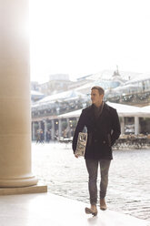 Young man carrying gift in Covent Garden, London, UK - CUF31659