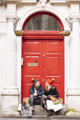 Junges Paar macht eine Pause beim Einkaufen vor der Haustür, London, UK - CUF31681