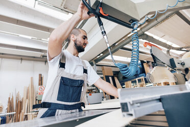 Low angle view of young man in workshop using carpentry equipment - CUF31707