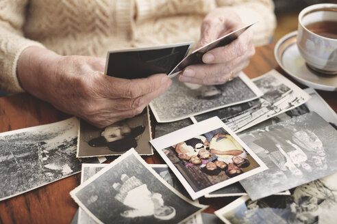 Ältere Frau am Tisch sitzend, alte Fotos durchsehend, Mittelteil - CUF31714