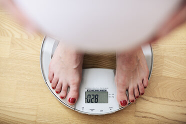 Pregnant woman standing on scales, overhead view - CUF31744