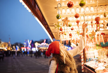 Young woman choosing baubles at xmas festival in Hyde Park, London, UK - CUF31765