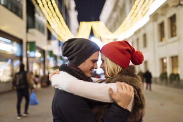 Romantic young couple hugging on street at xmas, London, UK - CUF31767