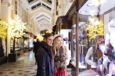 Young couple window shopping in Burlington Arcade at xmas, London, UK - CUF31768