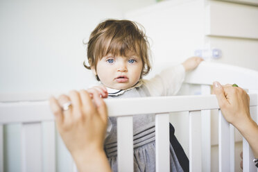 Portrait of female toddler staring from crib - CUF31774