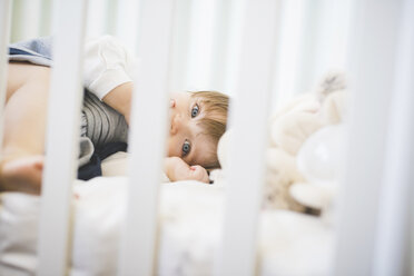 Female toddler lying in crib looking at camera - CUF31775