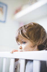 Portrait of female toddler gazing from crib - CUF31777