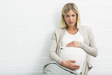 Portrait of full term pregnancy young woman sitting holding stomach - CUF31791