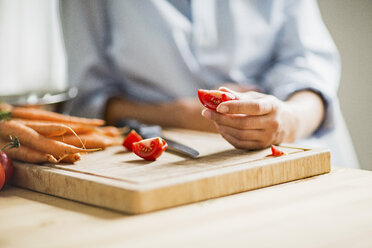 Abgeschnittene Aufnahme einer hochschwangeren jungen Frau, die in der Küche eine Tomate schneidet - CUF31801