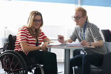 Teacher and female student in wheelchair having classroom tutorial - CUF31824