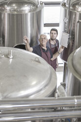 Brewers in brewery next to stainless steel tanks - ISF09722