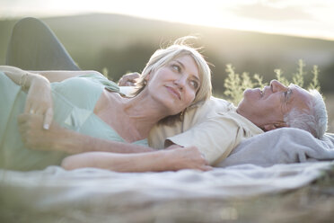 Älteres Paar liegt zusammen auf einer Decke im Freien - ISF09731