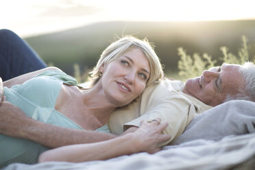 Mature couple lying together on blanket smiling - ISF09732