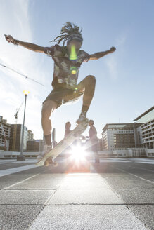 Junger Mann in städtischem Gebiet, der einen Trick auf dem Skateboard ausführt - ISF09737