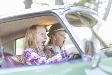 Two young girls driving car, looking scared - ISF09787