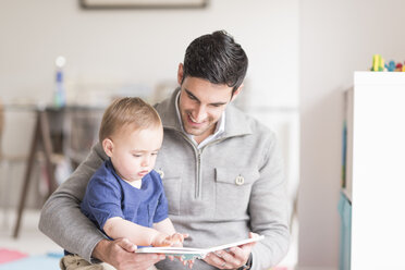 Father and young son reading book together - CUF31887