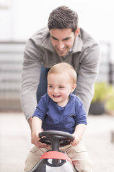Vater und kleiner Sohn spielen zusammen, Sohn fährt Spielzeugauto - CUF31888