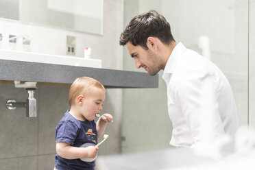 Father watching young brush teeth - CUF31895