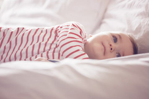 Kleiner Junge auf dem Bett liegend, lizenzfreies Stockfoto