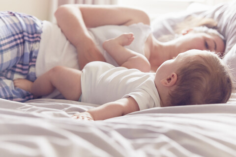 Mutter und kleiner Junge auf dem Bett liegend, lizenzfreies Stockfoto