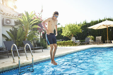 Junger Mann mit Schwimmbrille springt ins Schwimmbad - CUF32121
