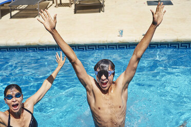 Portrait of young man and mother with hands raised in swimming pool - CUF32123