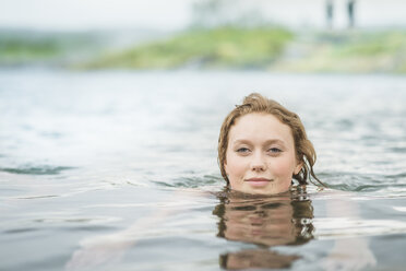 Porträt einer heiteren jungen Frau beim Schwimmen in der heißen Quelle Secret Lagoon (Gamla Laugin), Fludir, Island - CUF32160