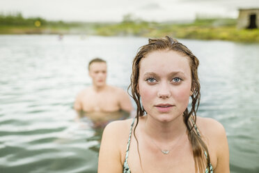 Porträt einer jungen Frau, die vor ihrem Freund in der heißen Quelle Secret Lagoon (Gamla Laugin) steht, Fludir, Island - CUF32162