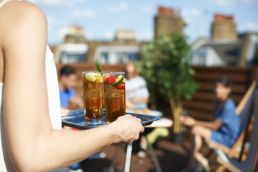 Frau trägt Tablett mit Cocktails auf einer Dachterrassenparty - CUF32234