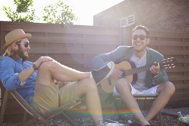 Zwei männliche Freunde spielen Gitarre auf einer Dachterrassenparty - CUF32238