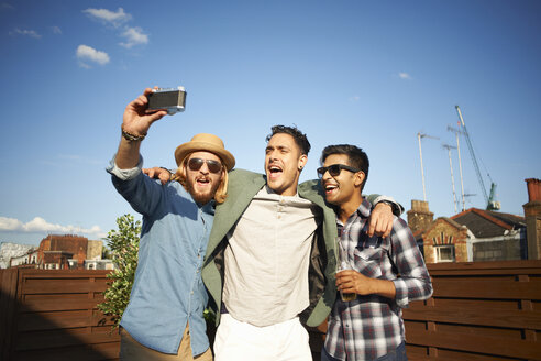 Drei männliche Freunde machen ein Kamera-Selfie auf einer Dachterrassenparty - CUF32240