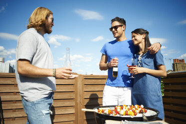 Paar unterhält sich mit einem männlichen Freund auf einer Dachterrassenparty - CUF32241