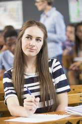 Portrait of female student, sitting at desk in classroom - CUF32272