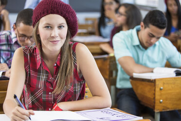 Porträt einer Studentin, sitzend am Schreibtisch im Klassenzimmer - CUF32274