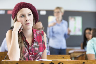 Studentin, sitzend am Schreibtisch im Klassenzimmer, nachdenklich - CUF32275