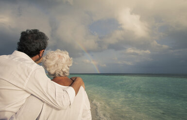 Älteres Paar mit Blick auf den Regenbogen über dem Meer, Malediven - ISF09809