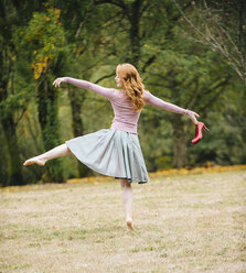 Rückansicht einer jungen Tänzerin, die mit roten High Heels im Park steht - ISF09838