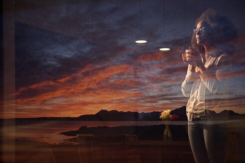 Frau schaut durch ein Fenster auf die Cuillin-Bergkette, Isle of Skye, Schottland - ISF09861