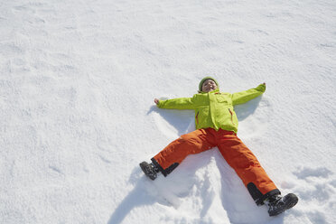 Young boy making snow angel in snow - ISF09880