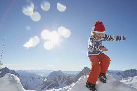 Junge steht auf einem Schneehaufen in einer verschneiten Landschaft, lizenzfreies Stockfoto