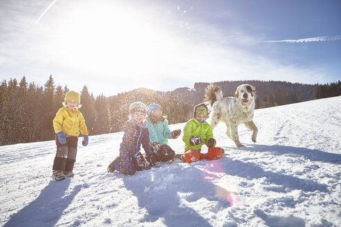 Kinder und Hund genießen das Spielen im Schnee - ISF09893