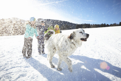 Kinder und Hund genießen das Spielen im Schnee - ISF09896