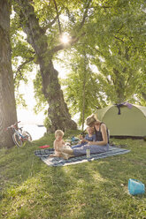 Mutter und Söhne entspannen sich auf einer Picknickdecke in ländlicher Umgebung - ISF09988