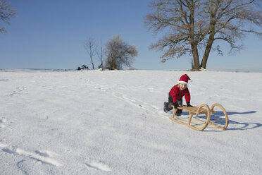 Young boy pushing sled down hill - ISF10014