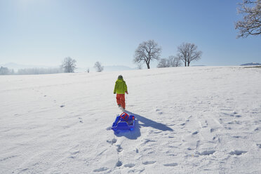 Junge geht im Schnee, zieht einen Schlitten hinter sich her, Rückansicht - ISF10019