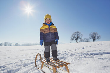 Portrait of young boy standing on sled in snowy landscape - ISF10021