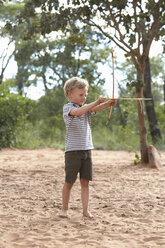 Junge auf Sand mit selbstgebautem Pfeil und Bogen - ISF10085