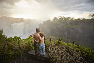 Zwei Jungen stehen auf einem Felsvorsprung und bewundern die Aussicht, Rückansicht, Victoriafälle, Livingstone, Simbabwe - ISF10093